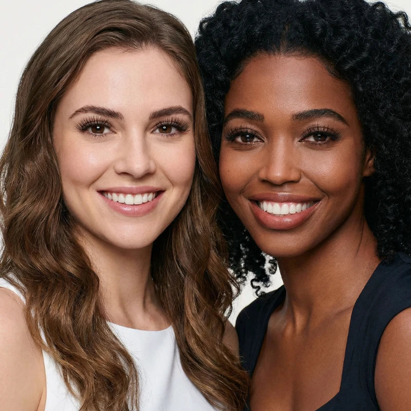 Duas mulheres sorrindo lado a lado, com cílios magnéticos aplicados, exibindo um olhar radiante e natural.