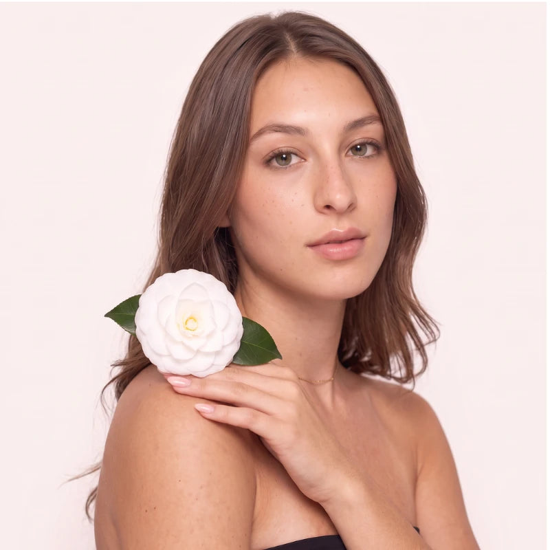 Modelo segurando flor de camélia branca, inspiração do design dos cílios magnéticos Cortezzo Camélia